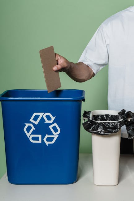 A large, overflowing pile of mixed household waste and litter covering an outdoor surface. The rubbish includes crumpled paper, plastic bags, discarded packaging, and metal or plastic containers. Some